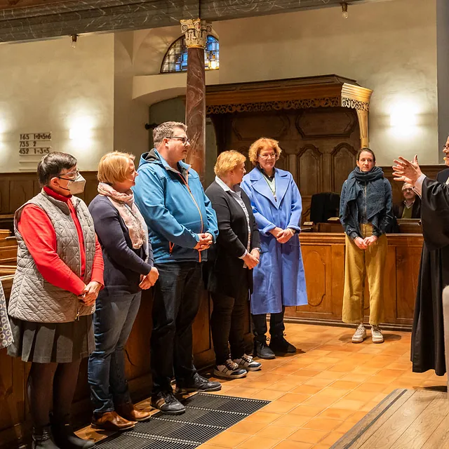 Gruppe lauscht Redner in Kirche.