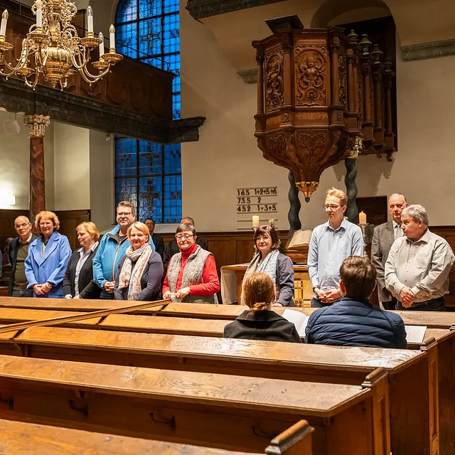 Eine Gruppe von Personen steht in einer Kirche vor dem Altar.