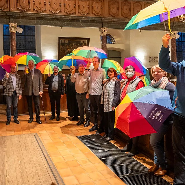 Gruppe mit bunten Regenschirmen in Kirche.