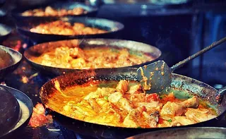 Mehrere Pfannen mit einem Eintopf oder Curry kochen auf einem Herd.