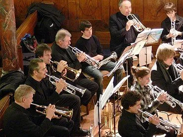 Eine Gruppe von Musikern spielt Blechblasinstrumente, hauptsächlich Trompeten.