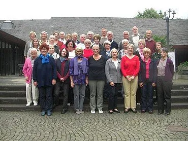 Große Gruppe älterer Erwachsener vor Gebäude im Freien.