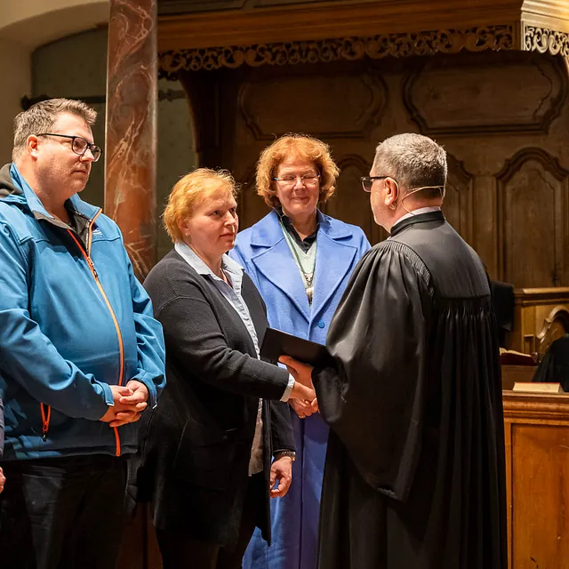 Frauen und Mann im Talar in Kirche.