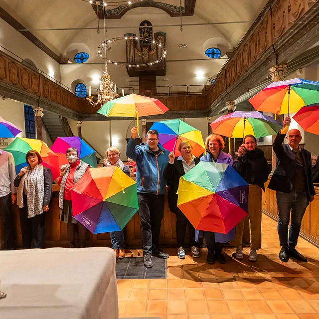 Personen mit bunten Regenschirmen in Kirche.