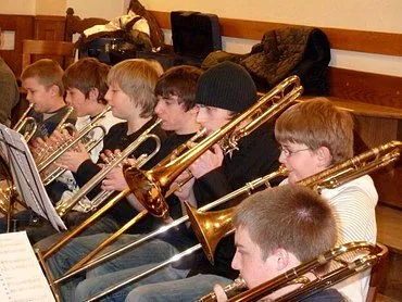 Eine Gruppe junger Musiker spielt Posaunen und Trompeten.