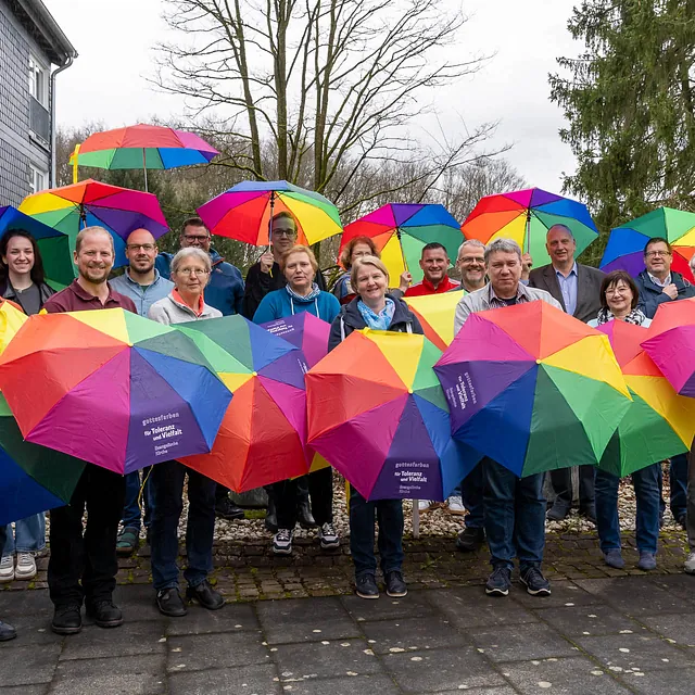 Gruppe mit bunten Regenschirmen im Freien.