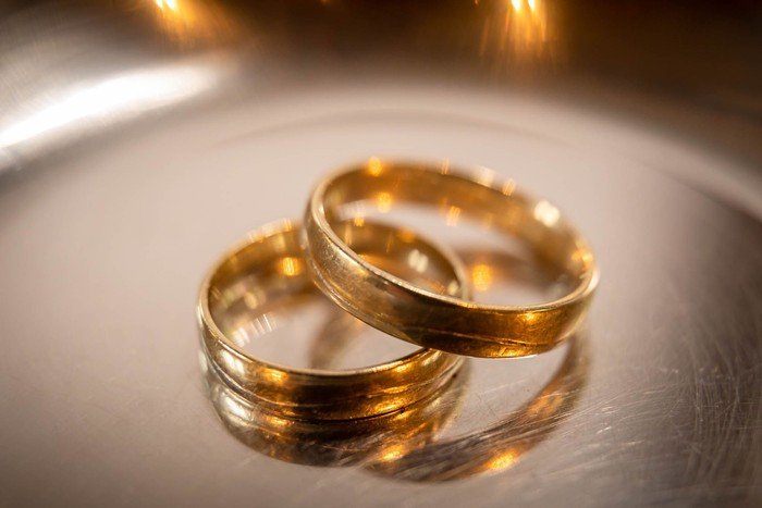 Zwei goldene Ringe liegen auf einer glänzenden Oberfläche.